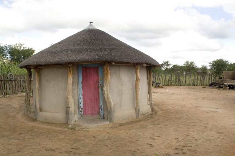 A traditional decorated rondavel with a thatched roof in a Botswana homestead