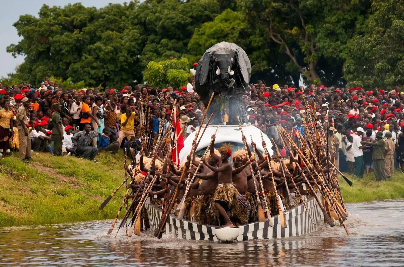Paddlers in red berets propel the royal barge at the Kuomboka ceremony, Zambia